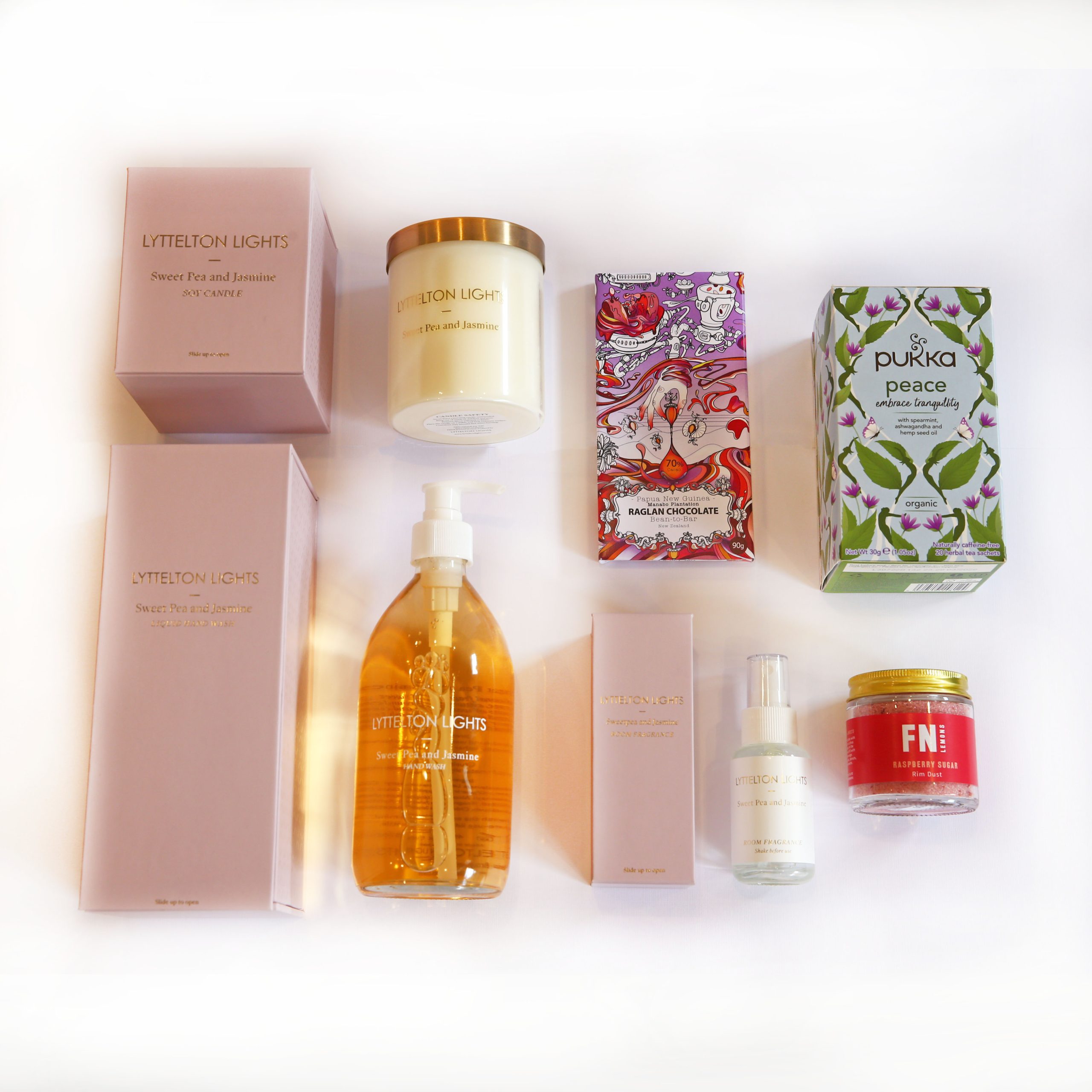 a group of gifts comprising of hand wash, room spray, candle, chocolate block, box of tea and a jar of cocktail rim duster.