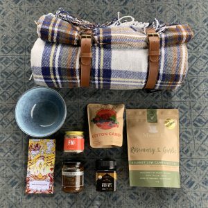 a picnic blanket, bowl and some food on display for a culinary gift box