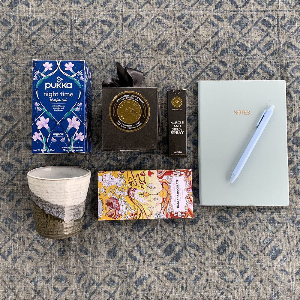 sleep tea, a tea cup, chocolate, stress spray and a note book and pen on display for a sympathy gift box