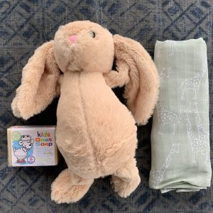 baby soap, a soft toy rabbit and a baby wrap on display