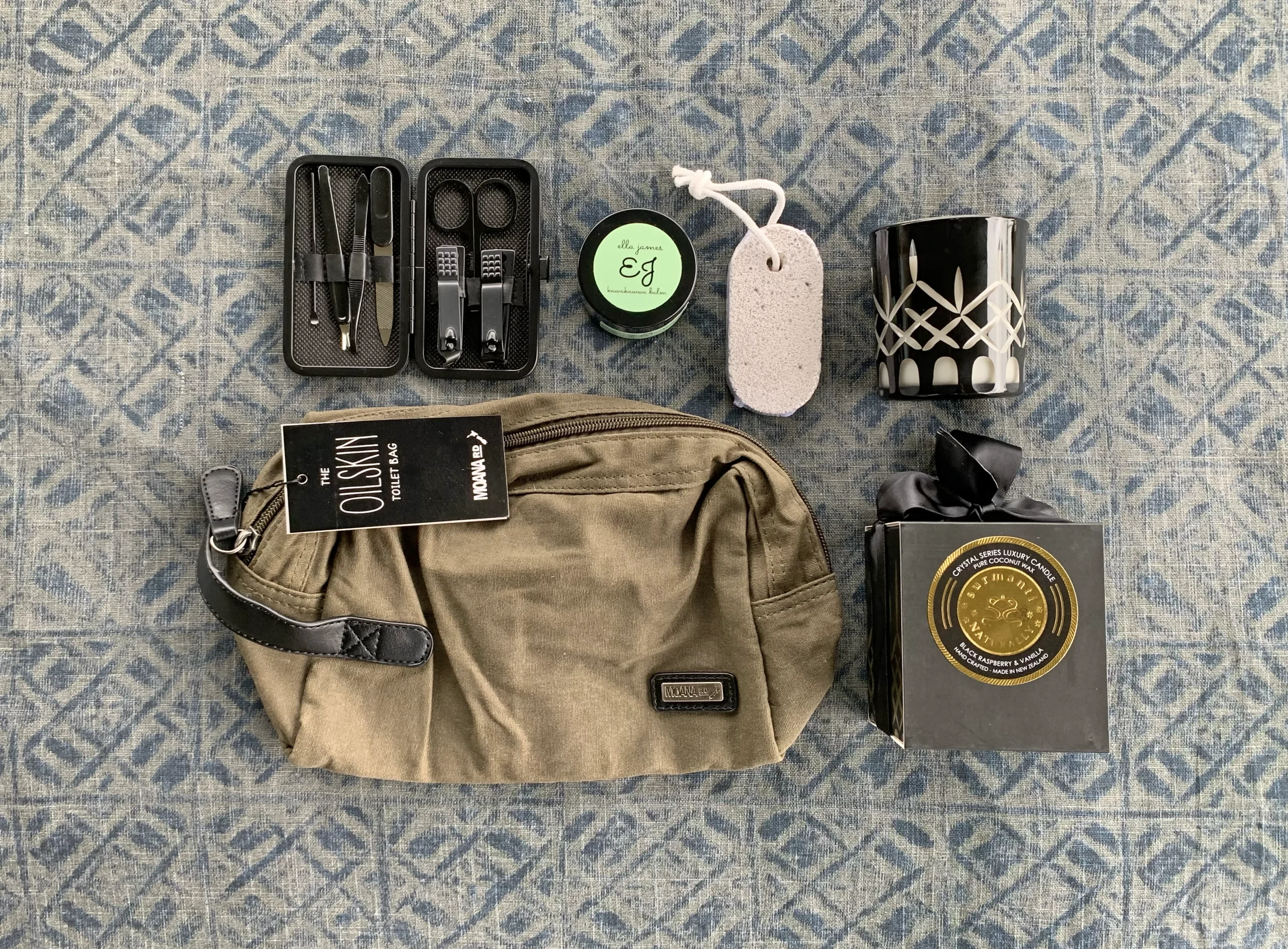 a toilet bag, manicure kit, balms and candles layed out on display
